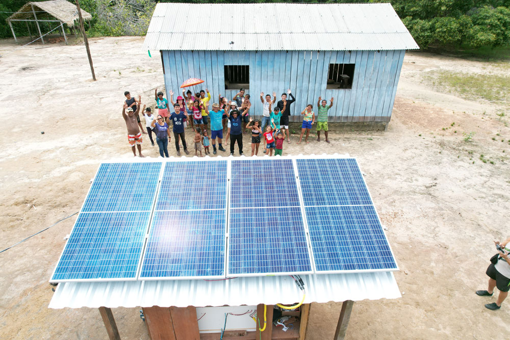 Villagers waving at drone flying over solar panels